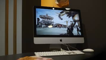 Una computadora de escritorio con monitor mostrando una escena, un teclado y un ratón sobre un escritorio.