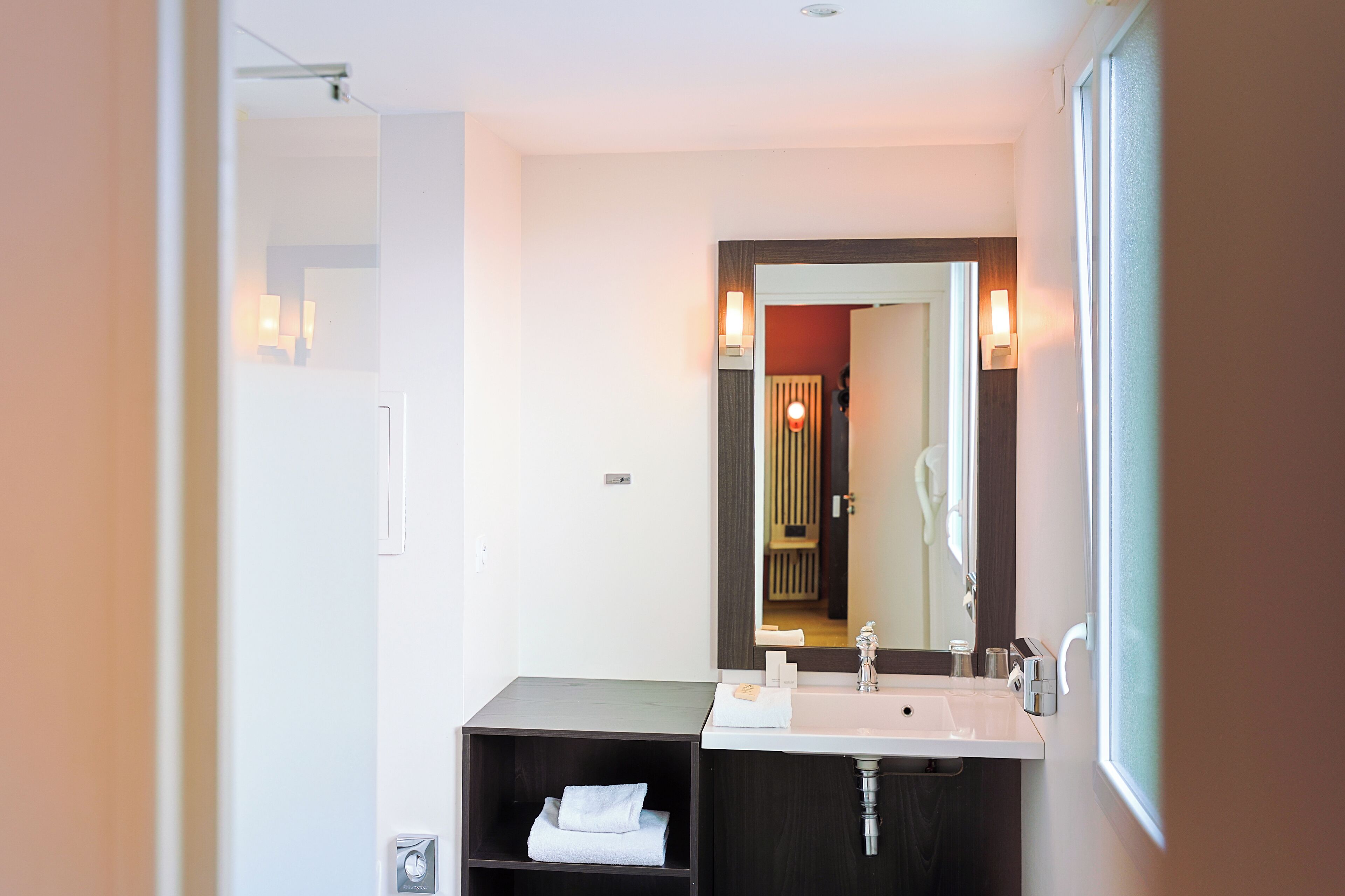A modern bathroom with a dual sink vanity, a large mirror, and a towel rack.