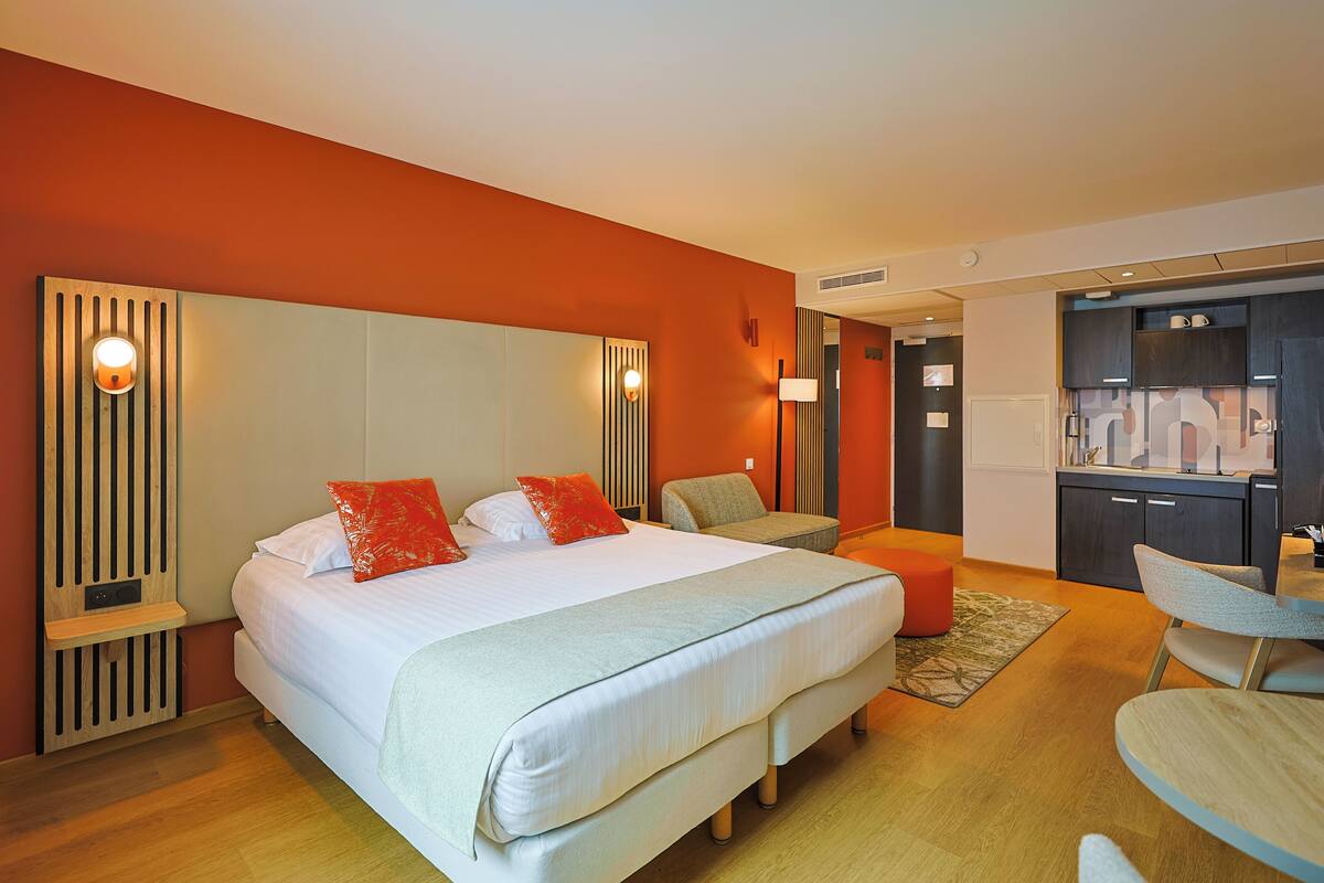 Een hotelkamer met een groot bed, een bureau en een kitchenette.