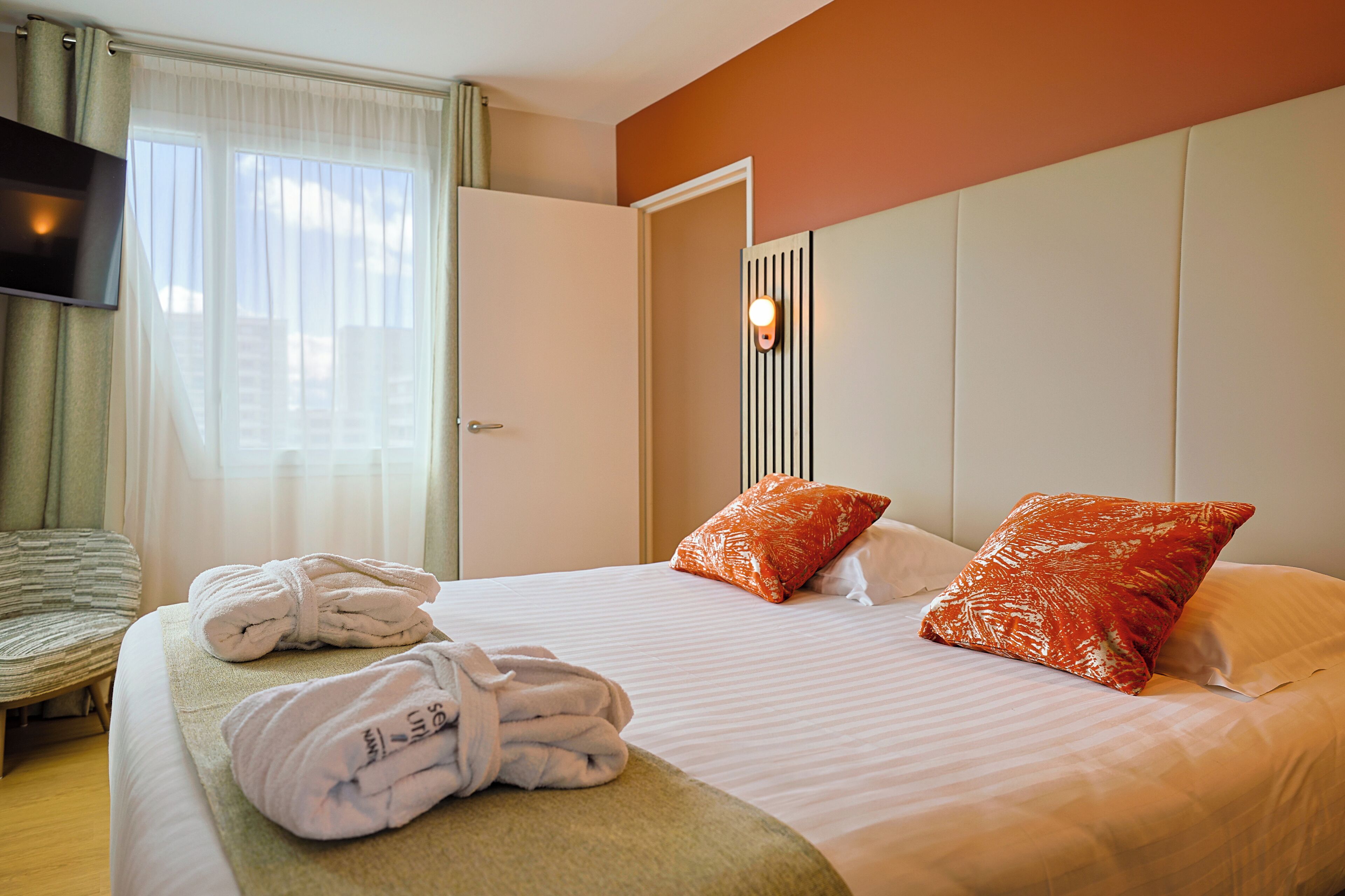 A hotel room with a bed, two pillows, a TV, and a pair of towels.