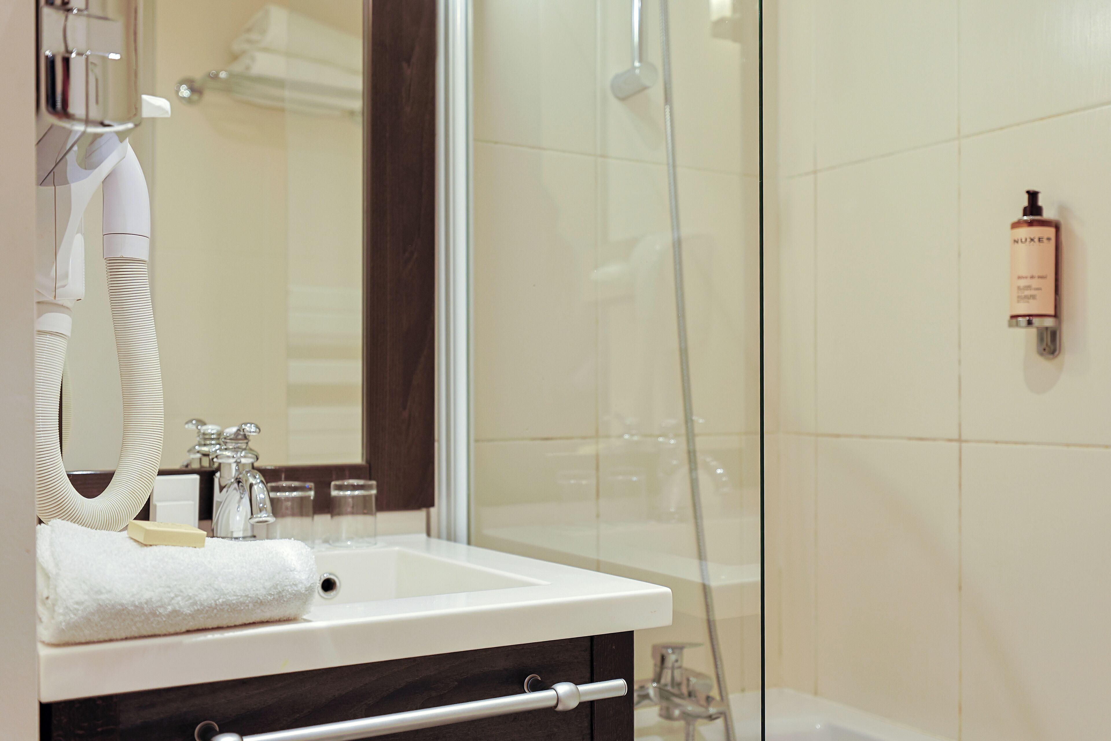 Un baño moderno con cabina de ducha de vidrio, lavamanos blanco y espejo.