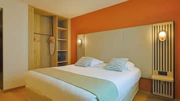 A bedroom with a bed, a wooden wardrobe, a shelf unit, and a wall-mounted light fixture.