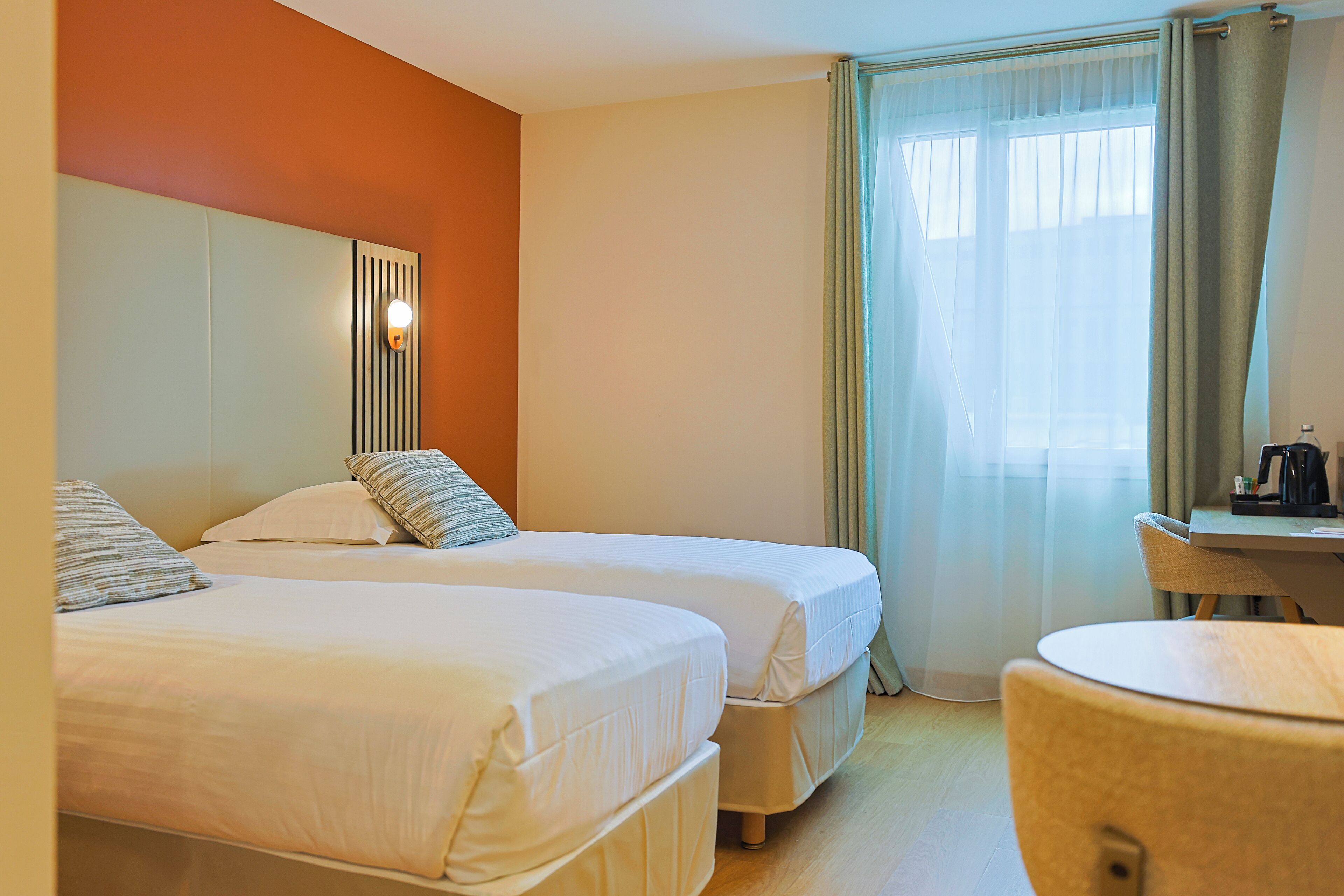Een hotelkamer met twee bedden, een bureau en een stoel.