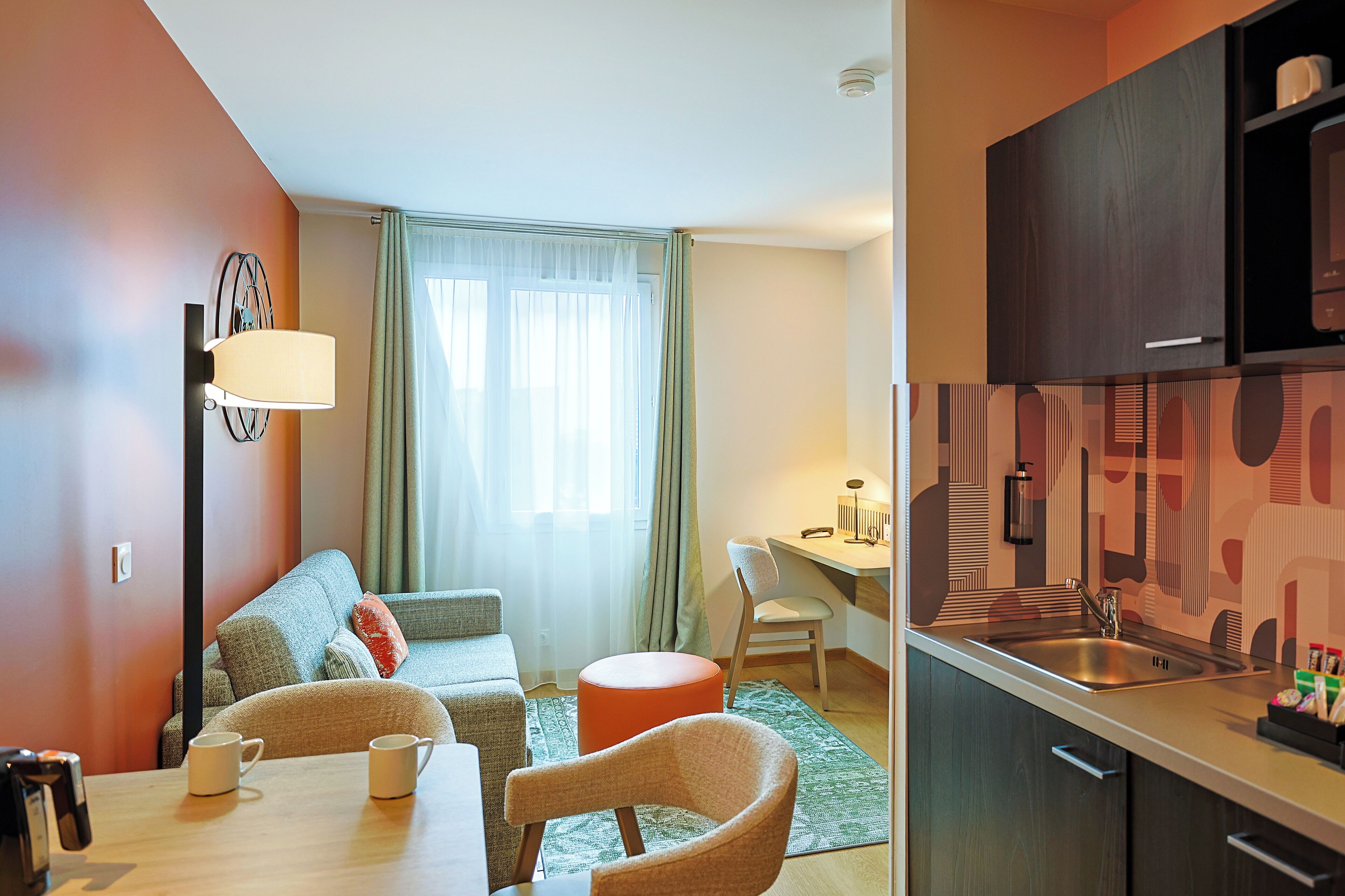 A compact living space with a dining area, kitchenette, and a sofa set.