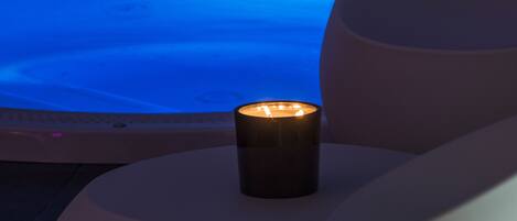 Un área de spa moderna con piscina climatizada y una vela encendida sobre un banco blanco.
