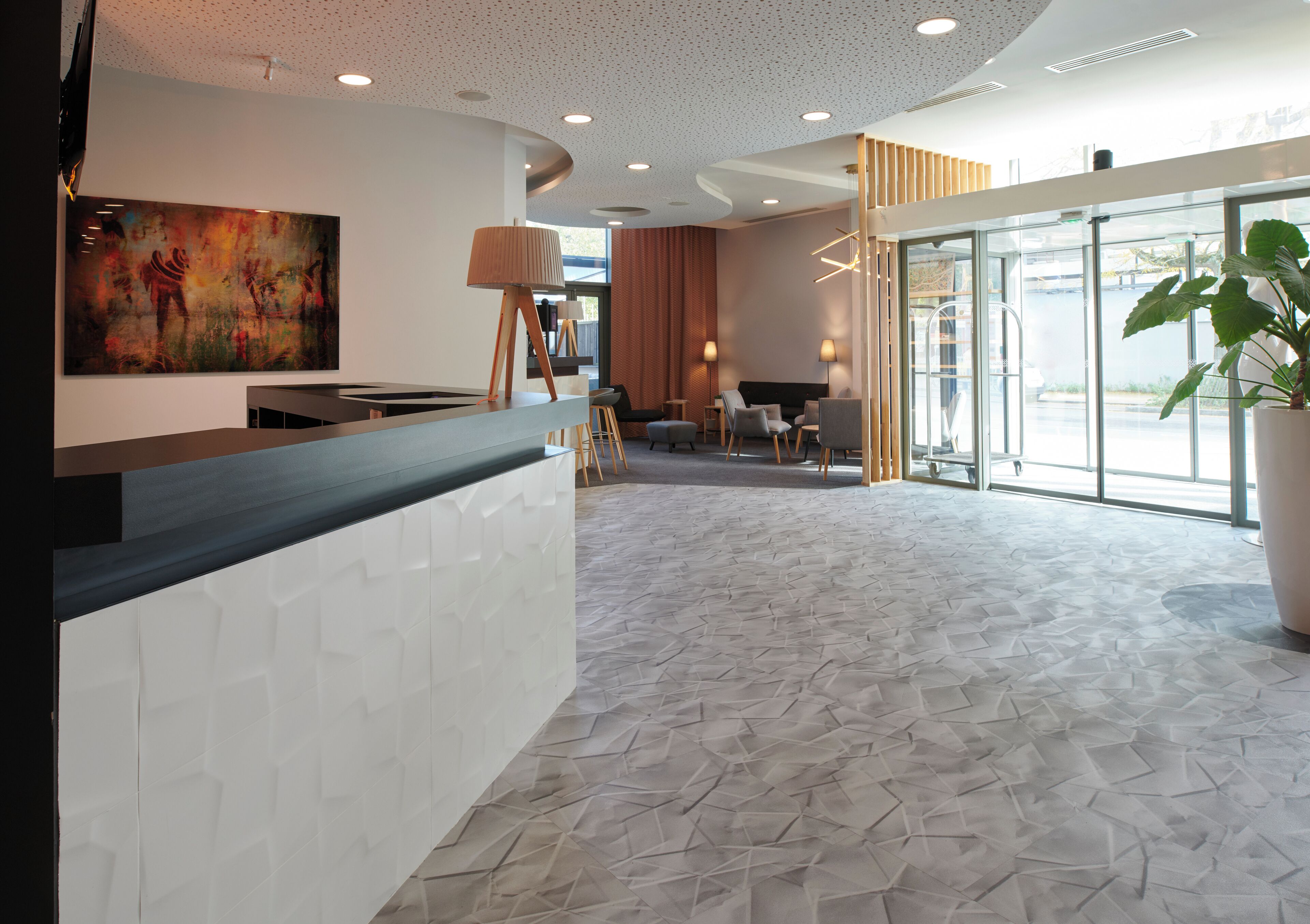 A modern reception area with a white reception desk, a large abstract painting, and a seating area with chairs and a table.