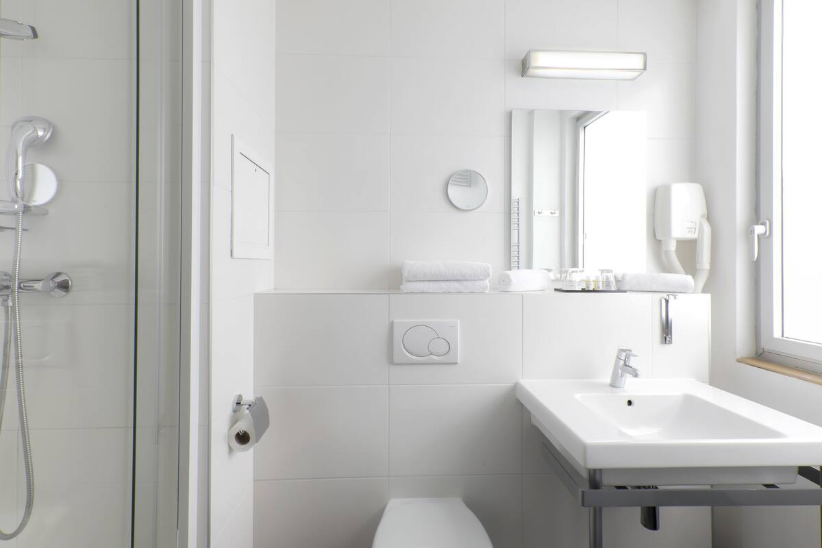 A modern bathroom with a glass shower enclosure, a white sink, and a mirror above the sink.