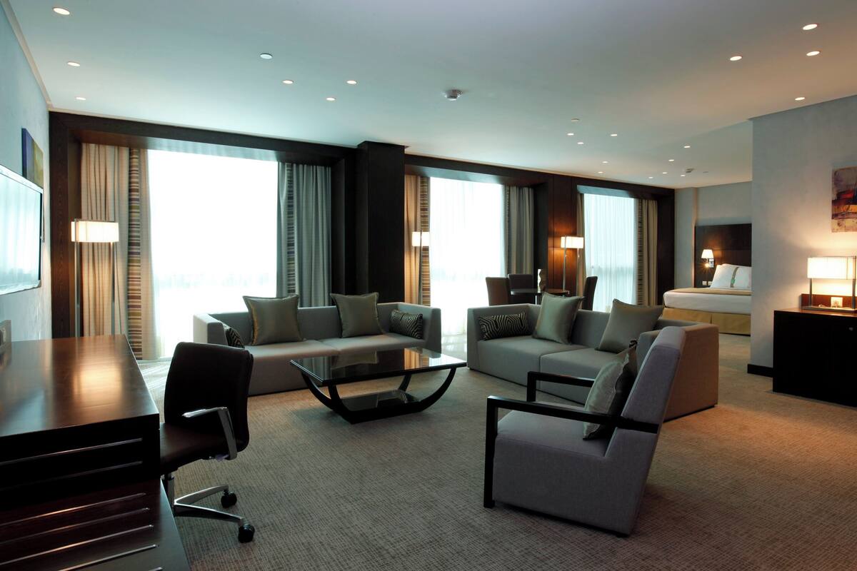 A modern hotel room with a sofa set, a desk, and a bed.