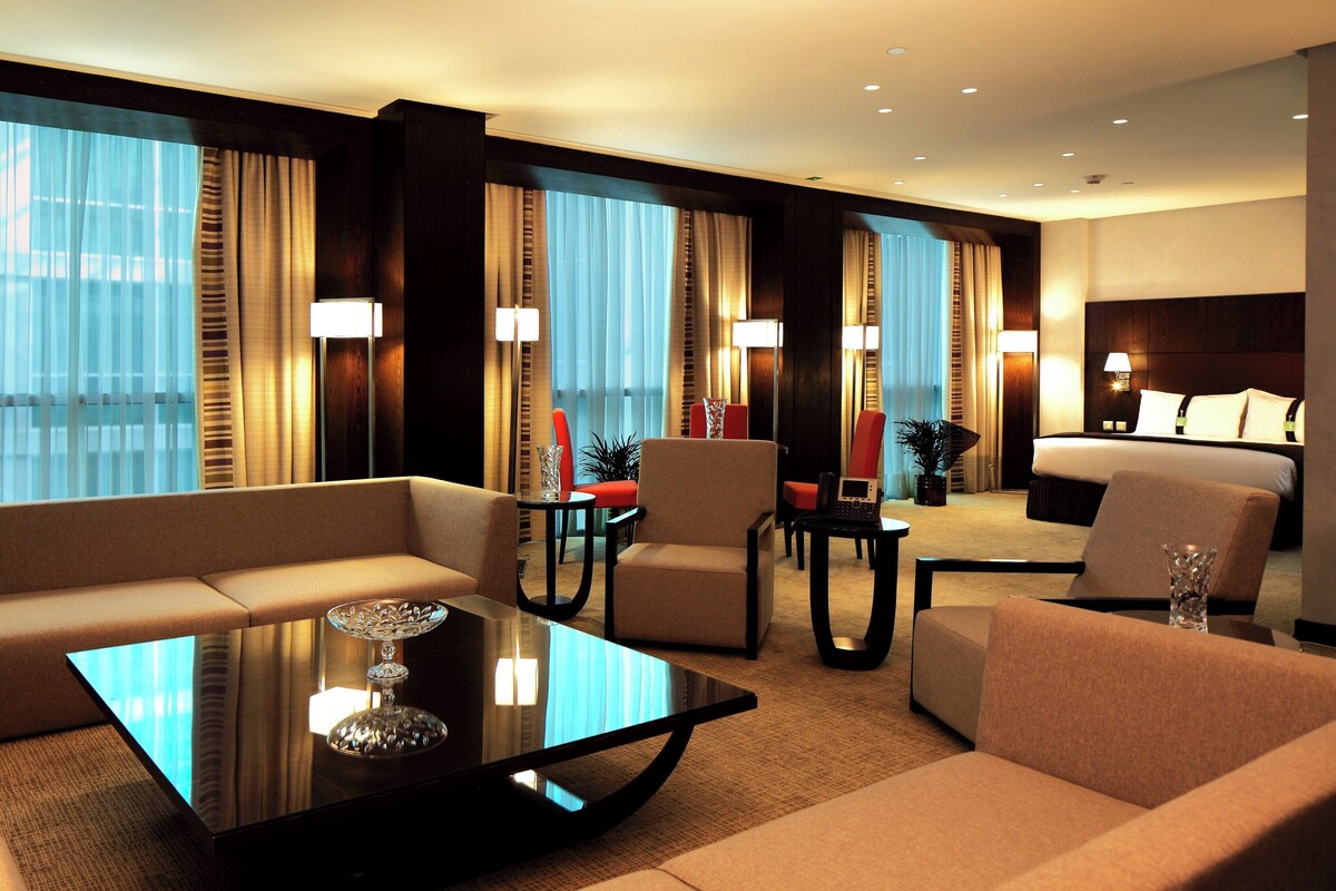 A hotel room with a sofa, armchairs, a coffee table, and a bed.