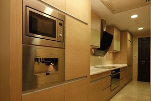 A modern kitchen with stainless steel appliances, wooden cabinetry, and a built-in oven. - Holiday Inn Riyadh - Meydan by IHG (Riyadh)
