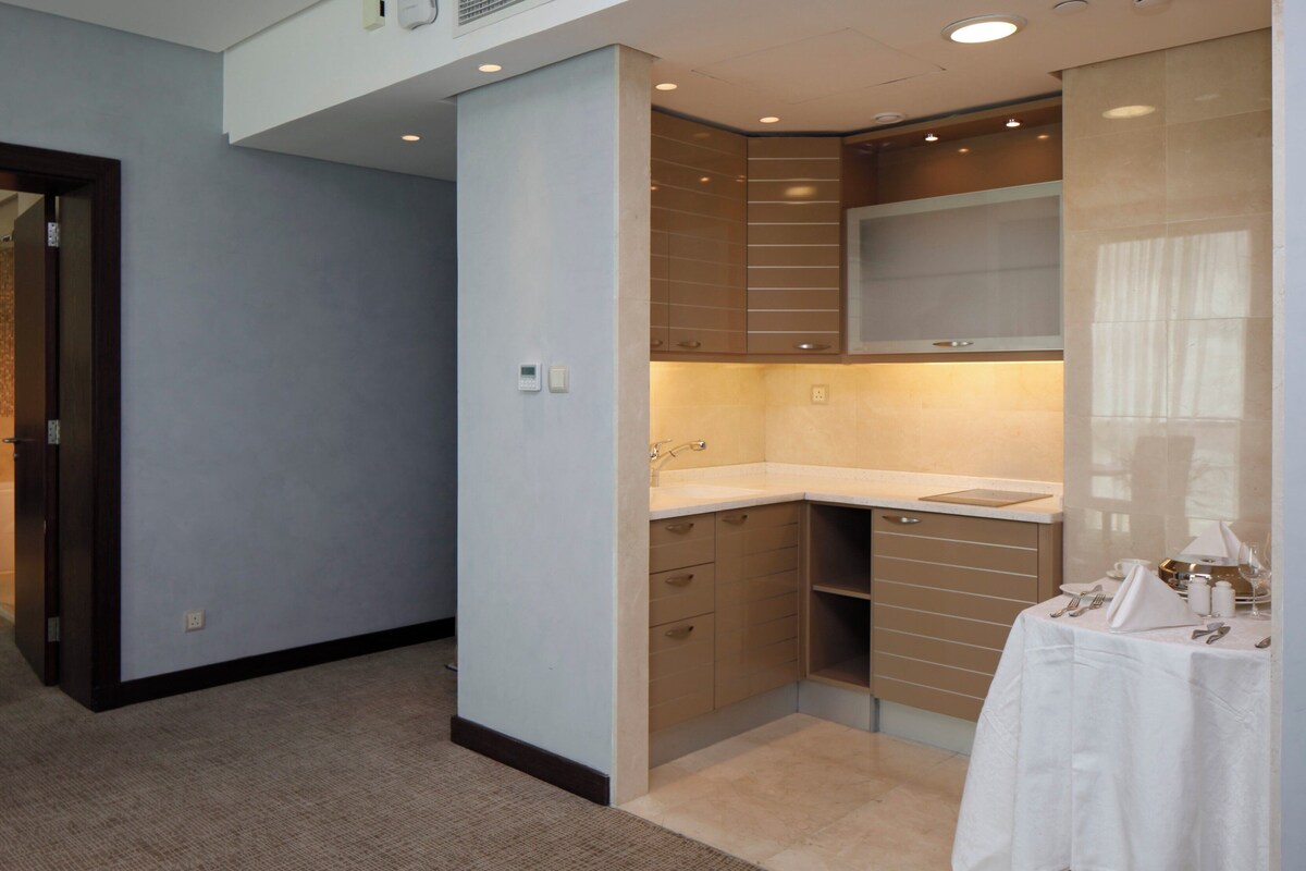 A modern kitchen with built-in appliances, a sink, and a dining area with a table set for two.