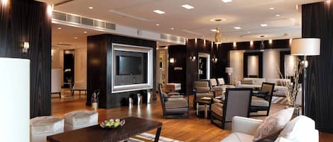 A modern living room with a flat-screen TV, comfortable seating, and a dining area.