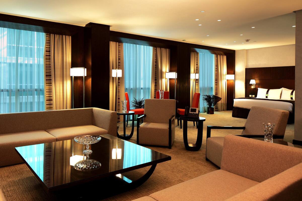 A hotel room with a sofa, armchairs, a coffee table, and a bed.