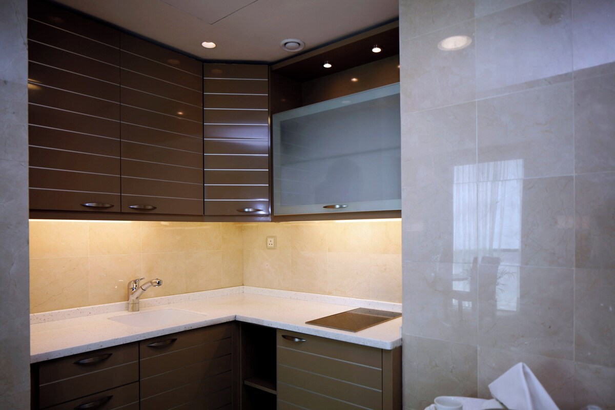 A modern kitchen with a corner sink, stainless steel appliances, and a backsplash.