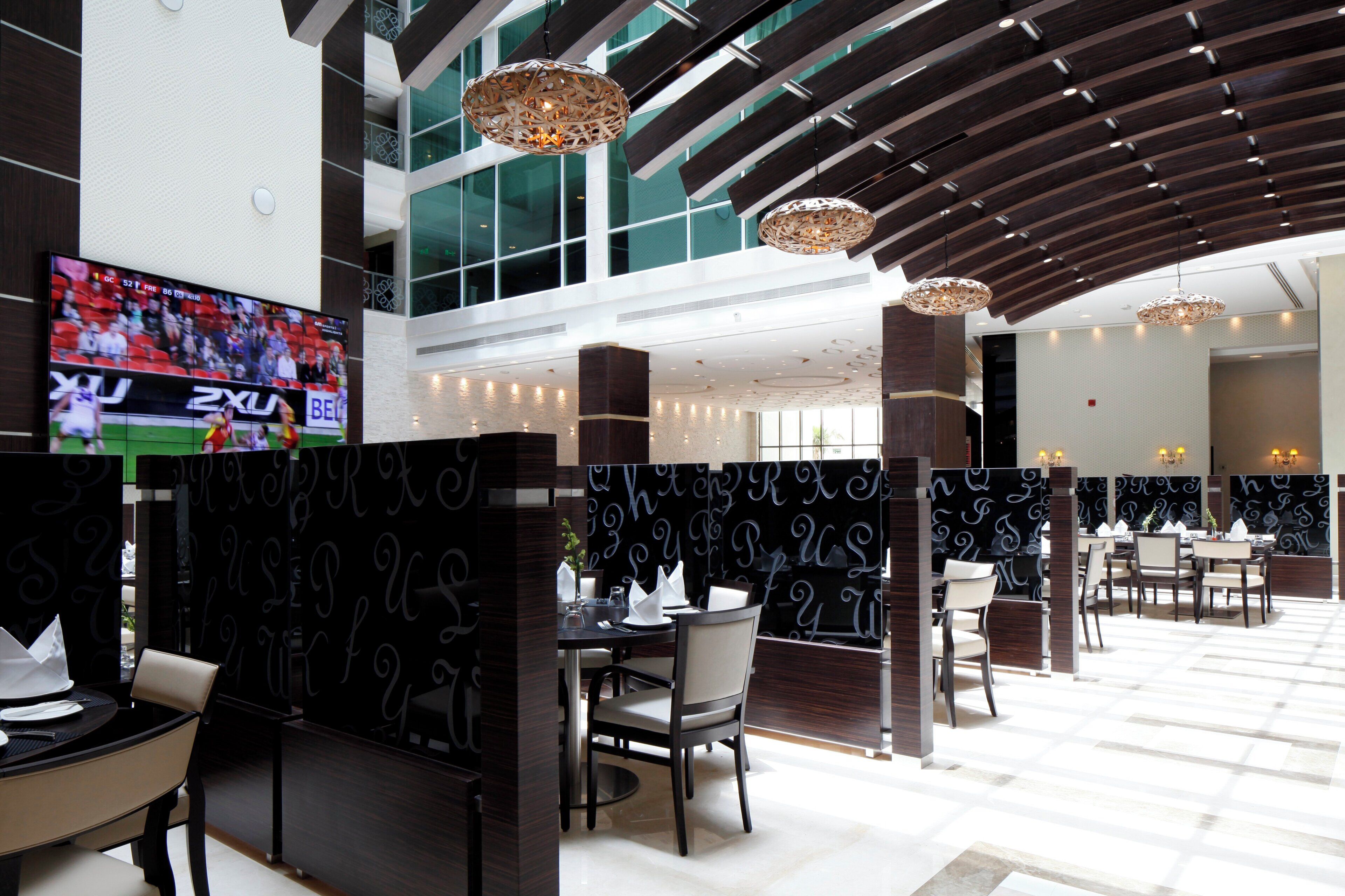 Un moderno vestíbulo de hotel con una gran pantalla de televisión, muebles elegantes e iluminación decorativa.