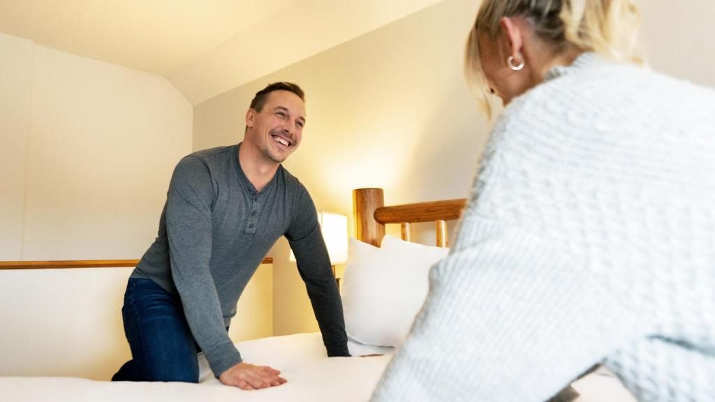 Ein Zimmer mit einem Bett, einem Holzkopfteil und einer Nachttischlampe.