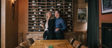A restaurant with a wooden wine rack, leather chairs, and a wooden table with a small plant.
