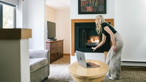 A living room with a fireplace, a sofa, a television, and a laptop on a small table. - Mountain Side Hotel Whistler by Executive (Whistler)