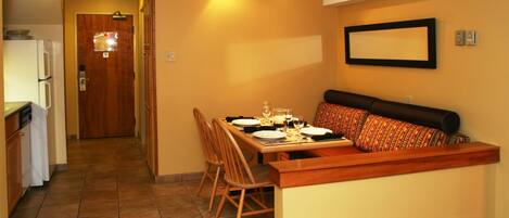 A compact kitchen with a dining area, a bench, and a tiled floor.
