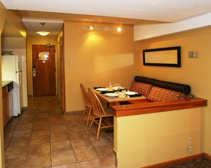 A compact kitchen with a dining area, a bench, and a tiled floor. - Mountain Side Hotel Whistler by Executive (Whistler)