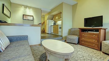 A living room with a sofa, a coffee table, a TV, and a patterned rug.