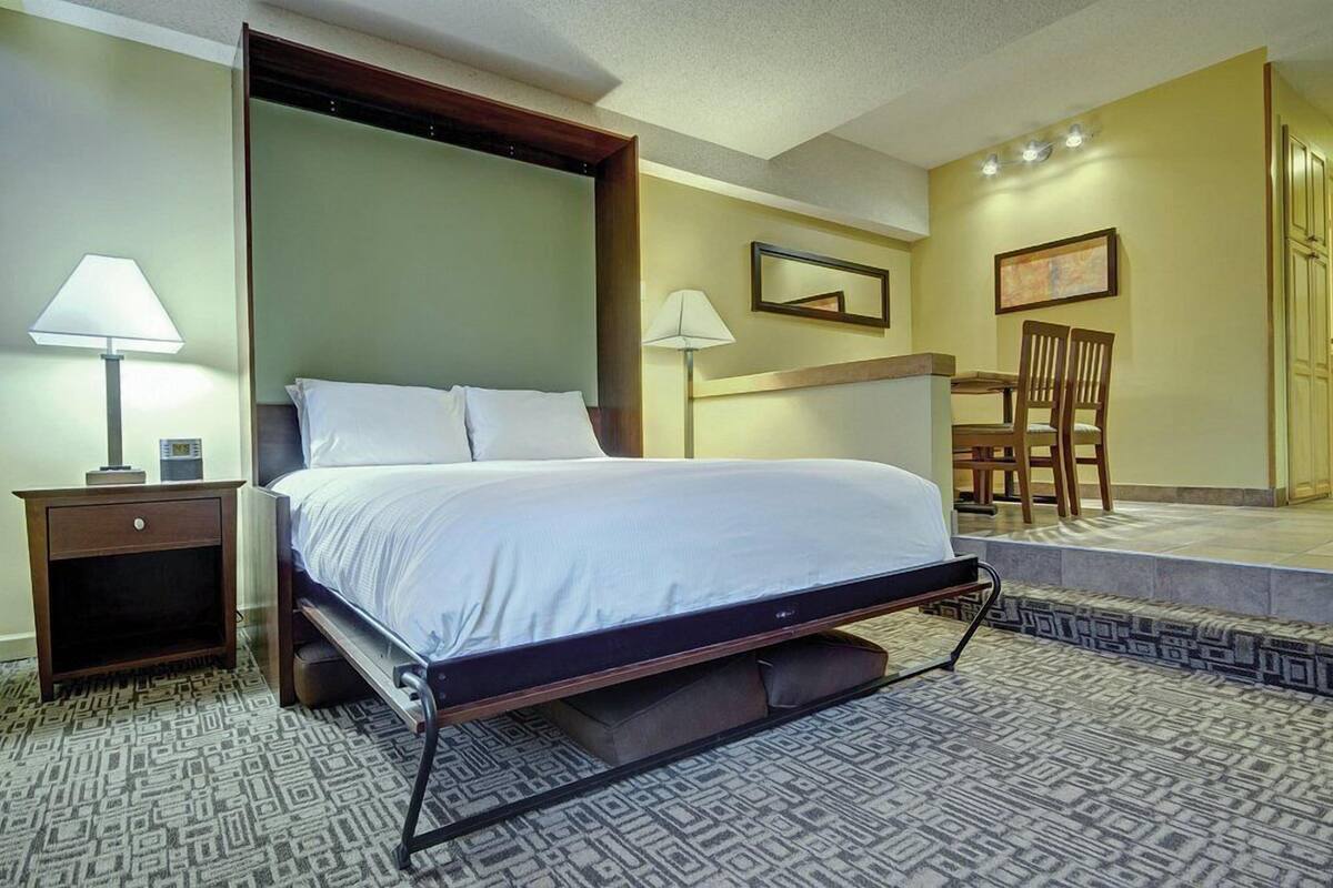 Habitación de hotel ordenada con una cama individual, mesitas de noche, una silla y una pequeña mesa.