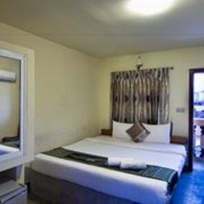 A hotel room with a bed, a bedside table, a mirror, and a window with curtains. - G Eleven Hotel (Phnom Penh)