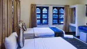 Ein Hotelzimmer mit zwei Betten, einem Schreibtisch und einem Fenster mit Vorhängen.
