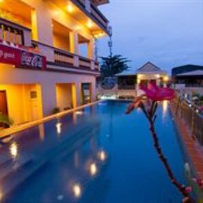 A hotel with a swimming pool, a Coca-Cola sign, and a building with balconies. - G Eleven Hotel (Phnom Penh)