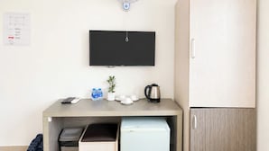 A compact room with a wooden desk, a small refrigerator, a TV, and a cabinet. - Hikari Stay - Bui Vien CBD (Ho Chi Minh City)