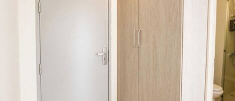 Una habitación con una puerta blanca, un armario de madera y una zona de ducha.