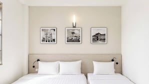 A hotel room with two beds, a light-colored headboard, and three black-and-white photographs on the wall. - Hikari Stay - Bui Vien CBD (Ho Chi Minh City)