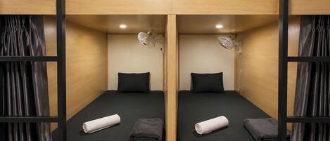 A bunk bed room with two beds, each with a pillow and a rolled towel.