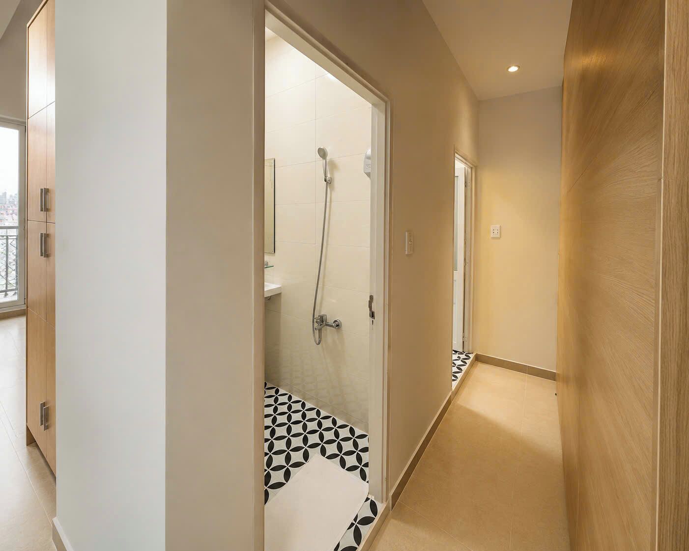 A modern bathroom with a glass shower door, a visible toilet, and a patterned floor.