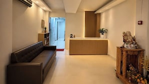 A modern hotel lobby with a reception desk, a seating area, and a decorative statue. - Hikari Stay - Bui Vien CBD (Ho Chi Minh City)
