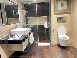 A modern bathroom with a glass-enclosed shower, a white toilet, and a vanity with a mirror.
