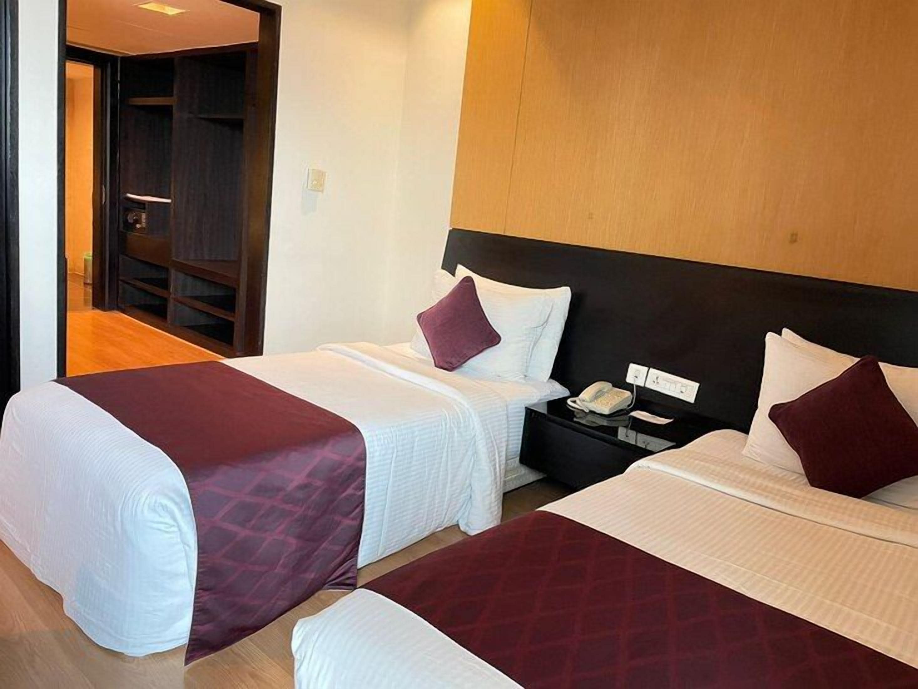 A hotel room with two beds, a nightstand, and a wooden headboard.