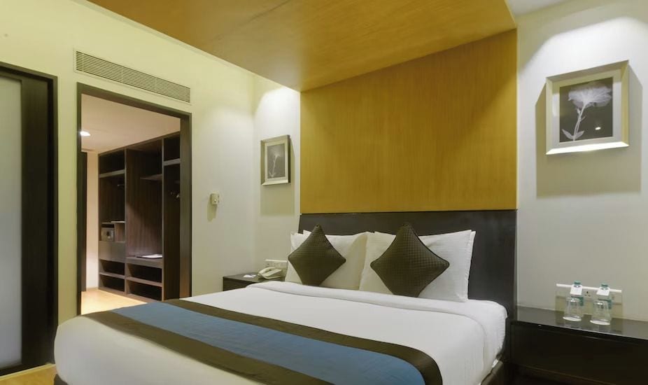 A hotel room with a bed, bedside table, nightstand, and a wardrobe.