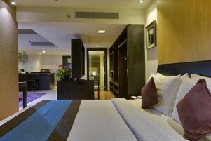 A hotel room with a bed, a desk, and a kitchenette.
