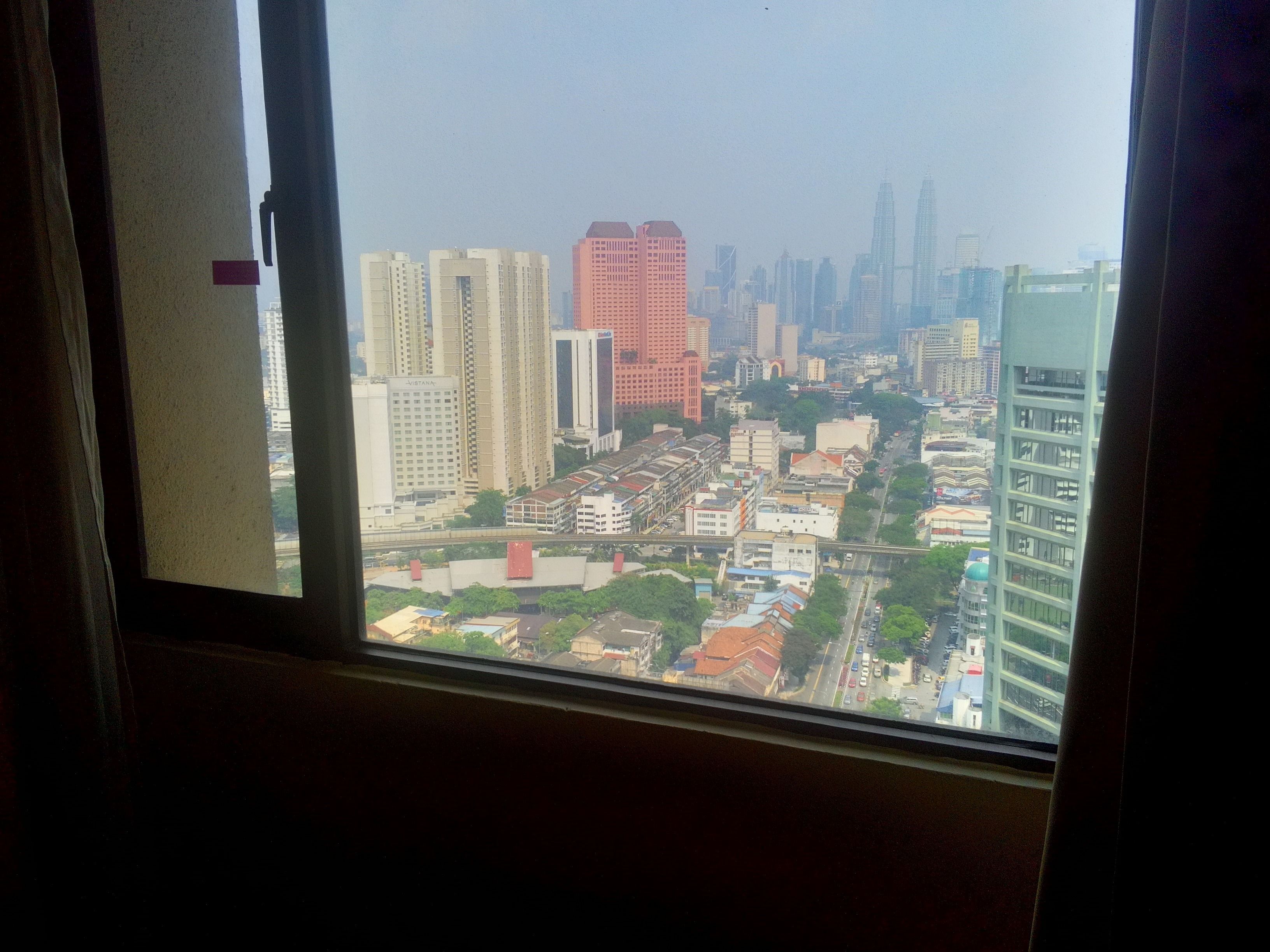 A cityscape through a window with high-rise buildings in the background.