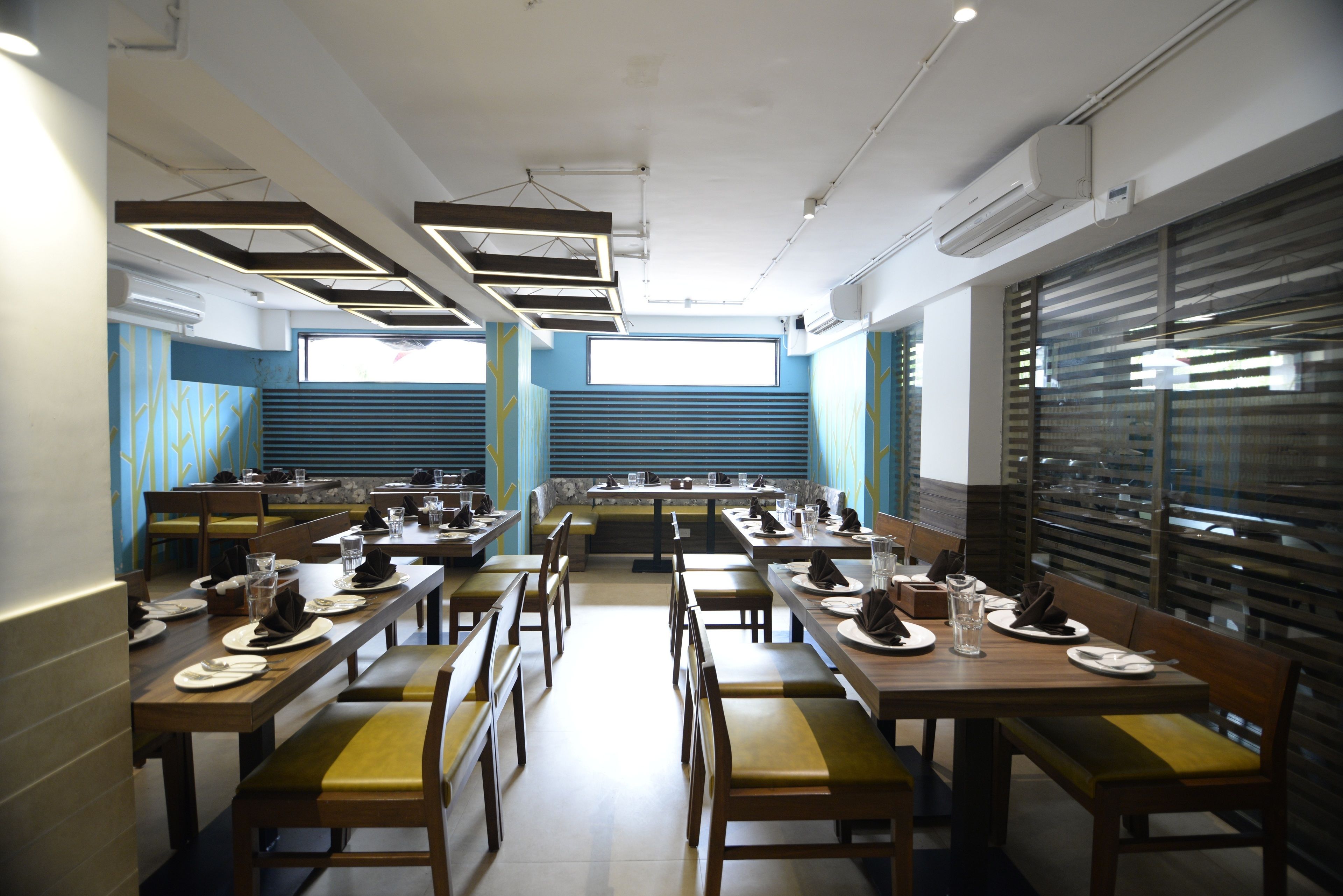 A restaurant with multiple tables and booths, air conditioning units, and a window with blinds.