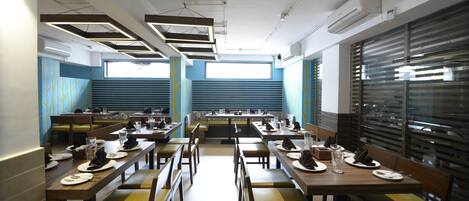 A restaurant with multiple tables and booths, air conditioning units, and a window with blinds.