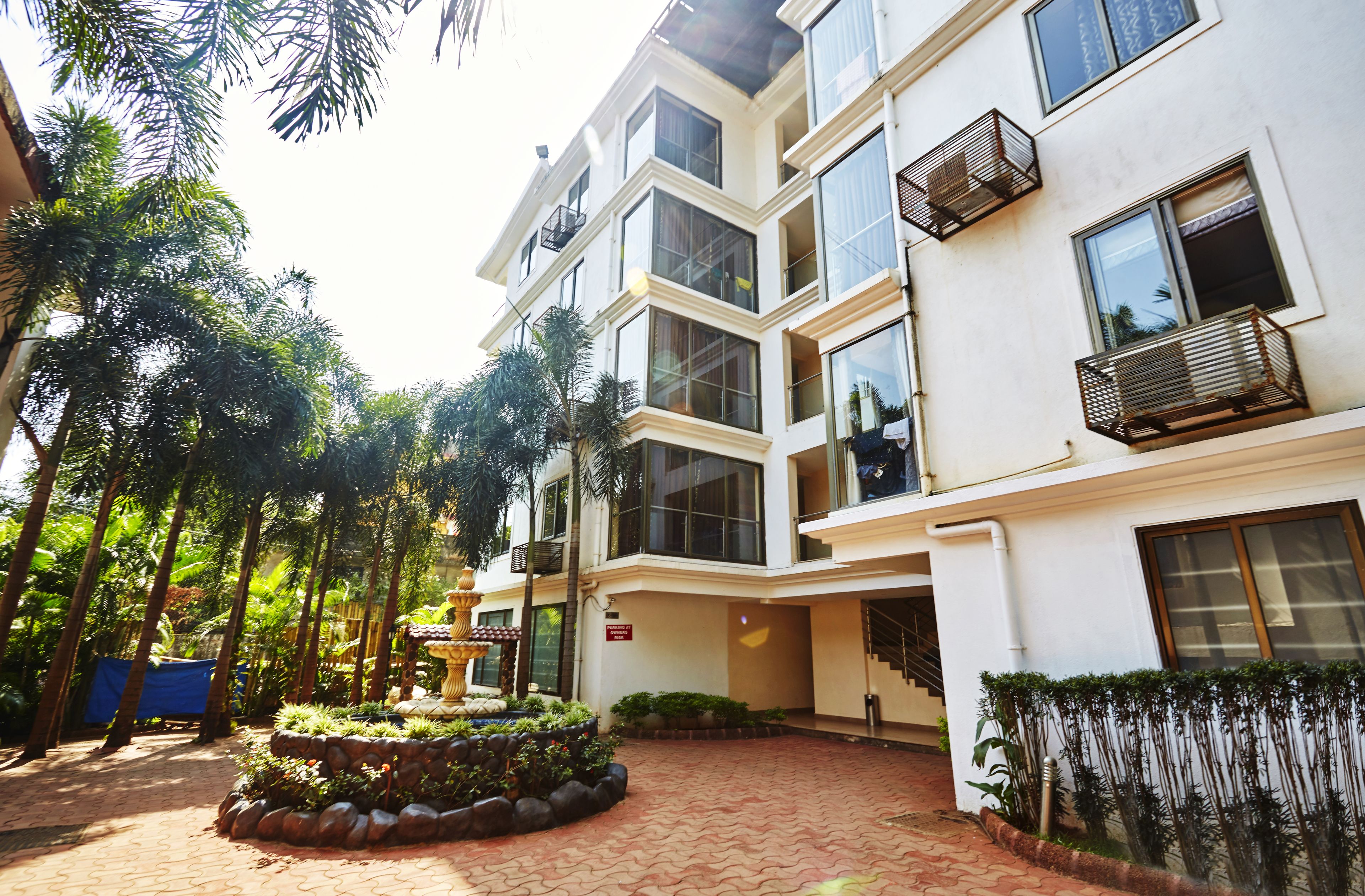 A multi-story hotel with a central courtyard, surrounded by lush greenery and palm trees.