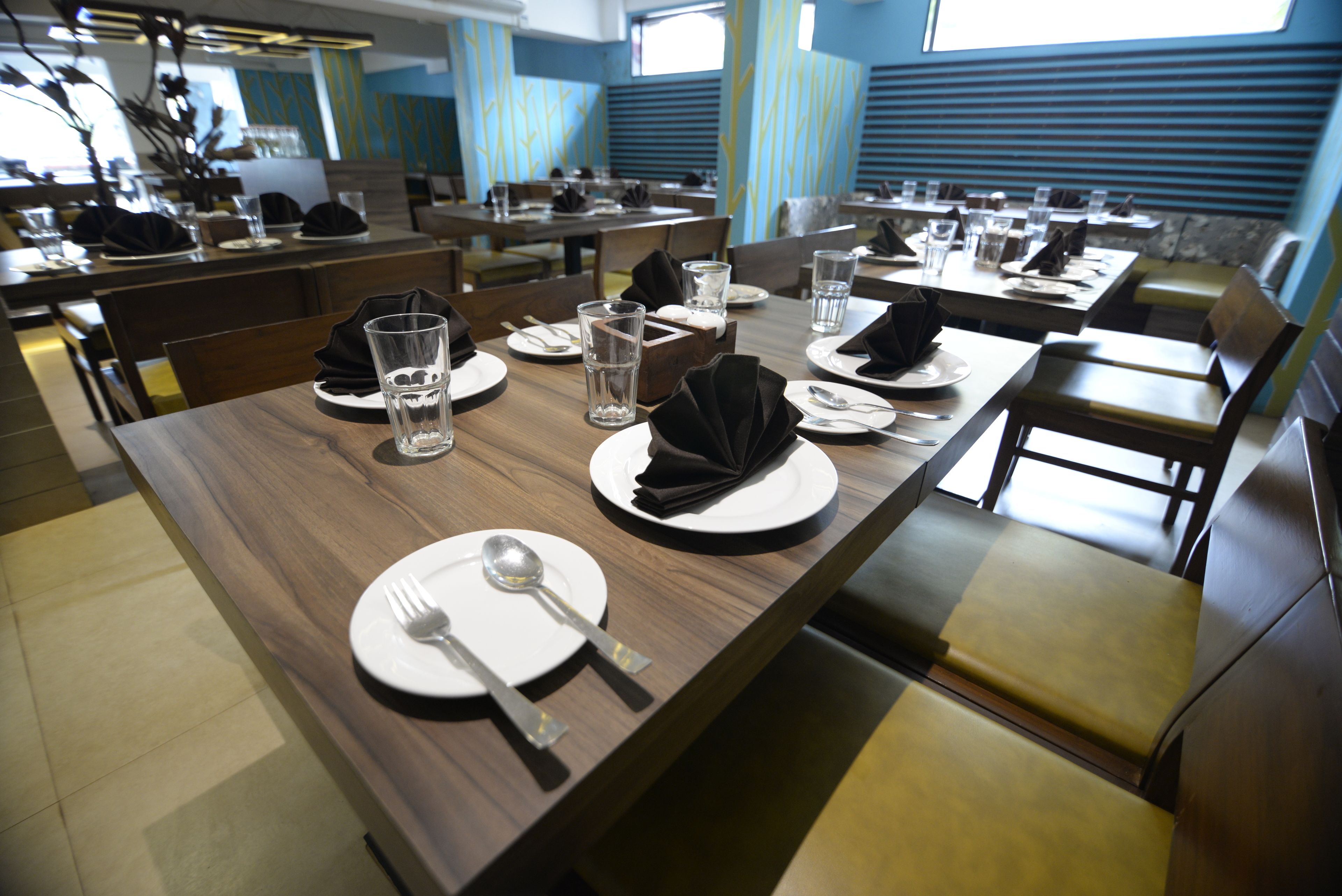 Un restaurant avec plusieurs tables, chacune mise avec des assiettes, des couverts et des verres.