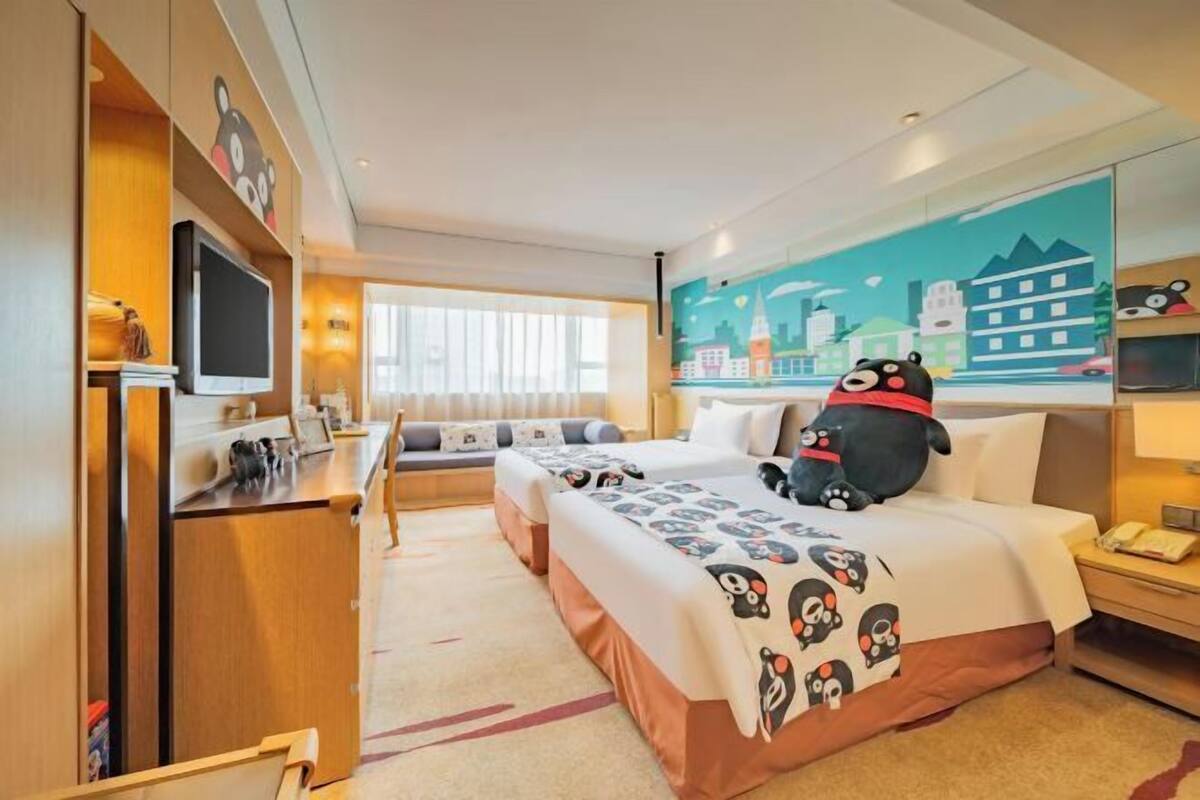 Ein Hotelzimmer mit Bett, Schreibtisch, Fernseher und einer Stadtbild-Wandmalerei.