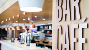 A bar café interior with pendant lighting, a counter, and wooden wall decorations. - Travelodge Ipswich (Ipswich)