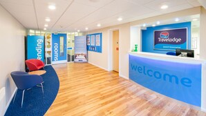 A modern reception area with a 'Welcome' sign, a 'Travelodge' logo, and a 'Rooms' sign indicating available accommodations. - Travelodge Ipswich (Ipswich)