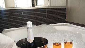 A hot tub with two glasses of champagne, a bottle of champagne, and a towel.