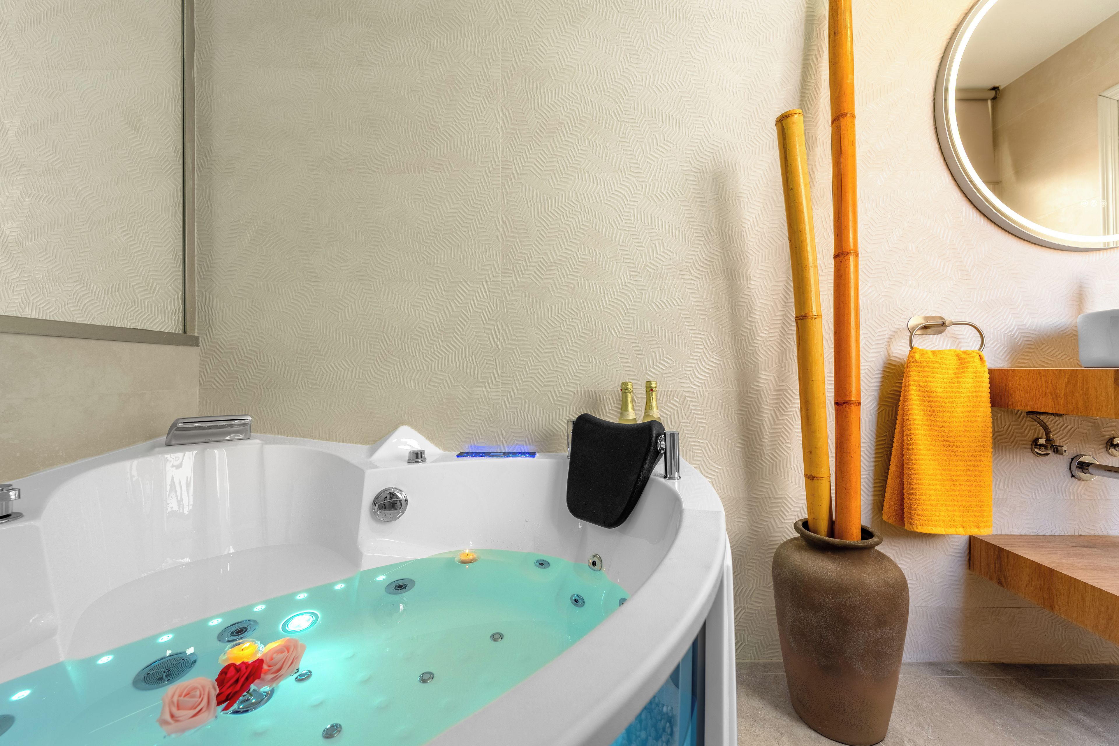 A bathroom with a bathtub, a mirror, a towel rack, and a vase with flowers.