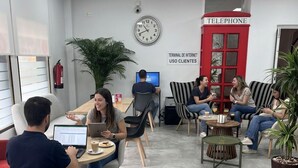 Un bureau moderne avec une horloge, un téléphone et une pancarte indiquant « Borne Internet à l’usage des clients ».